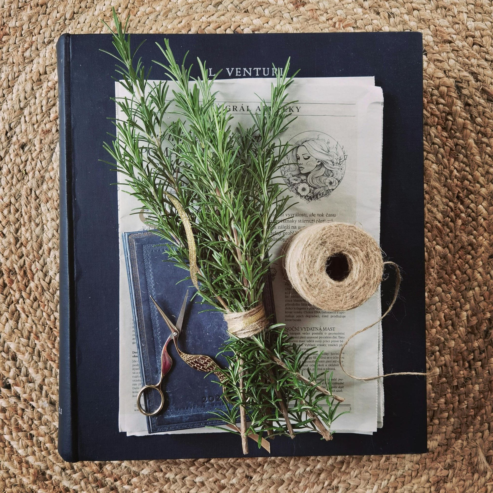 Bündel Rosmarin liegt auf einem Buch Naturband und feine Schere Gewürz Rezept oelfaktorisch körperöle